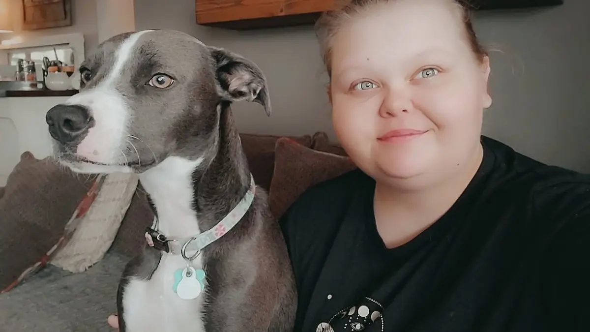 Emily sitting beside a gray-and-white dog at home.